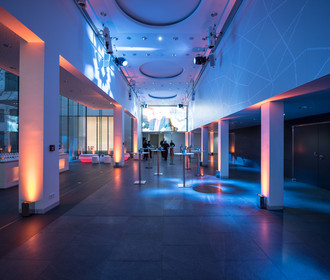 Stimmungsvolles Licht im Foyer der ConferenceArea im Haus der Bayerischen Wirtschaft. Die Halle mit weißen Säulen ist in stimmungsvolles blaues Licht gebadet. Auf der LED-Wand ist ein zur Veranstaltung passendes Bild eingespielt.