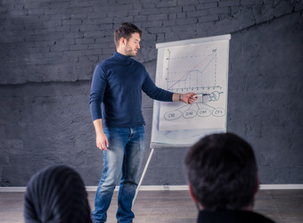 A young man presents with a flipchart to the participants of a conference event