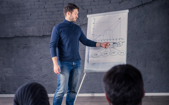 Ein junger Mann präsentiert mit einem Flipchart zu den Teilnehmern einer Konferenz Veranstaltung